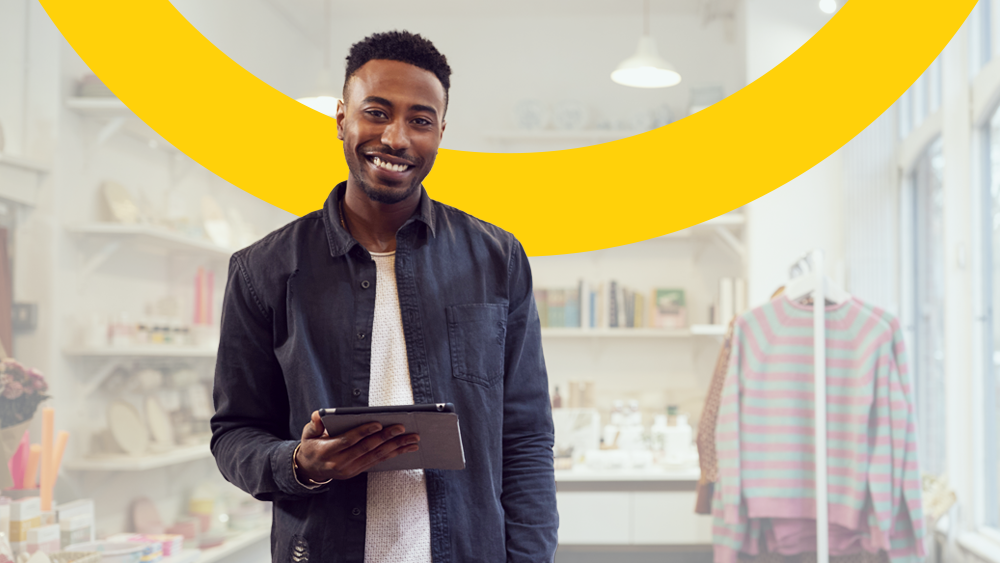 A shop owner with a tablet smiling while preparing for Making Tax Digital